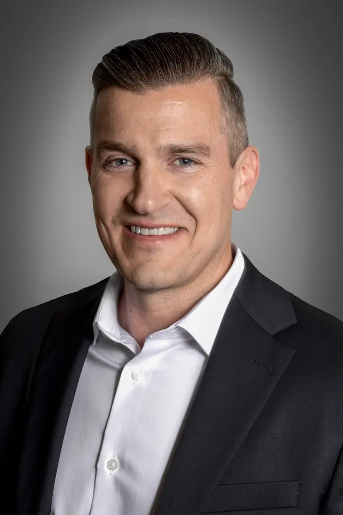 Professional headshot of Rob Bennett, a realtor, wearing a white shirt and dark suit, smiling confidently.